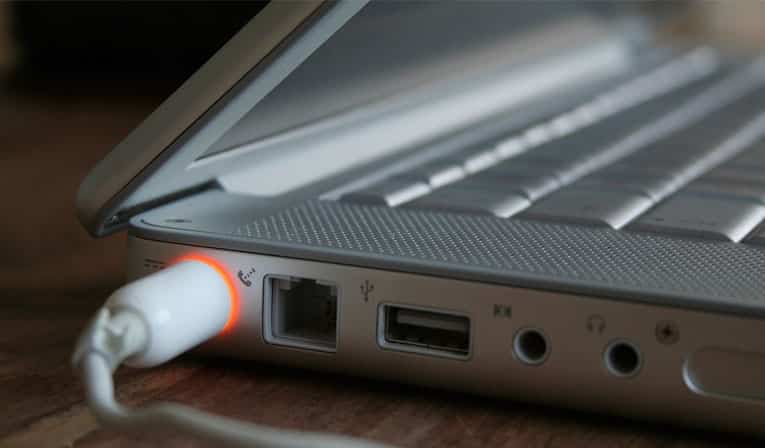 Side photo of a laptop with the power cord plugged in