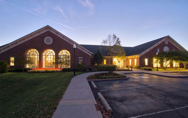 The front of the Zionsville library at night with the lights on